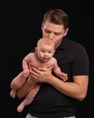 dad holds a naked baby in his arms and gently kisses. father's love and care