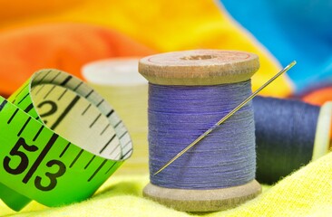 sewing item tools isolated on colored clothing with macro details including spools of thread, needle