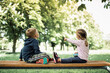 © kieferpix - Little boy and girl sitting on park bench relaxing enjoying nature