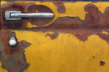photo of the texture of an old rusty dirty yellow car door. car door handle. detail of a retro car i