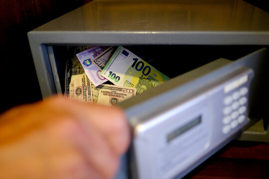 euro banknotes of european union, american dollars, tourist puts money in hotel mini safe with elect