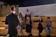 © Roman - happy group of people clapping hands after listening the conference in lecture hall. Rear view on successful caucasian male speaker in formal black suit. focus on male, view from back. copy space
