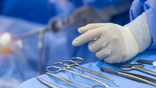 A Surgeon Or Doctor With Nurse Team In Blue Uniform Did Surgery Inside Operating Room In Hospital.Surgeon Picking Up Surgical Clamps And Medical Equipment With Light.Emergency Surgery Was Done.