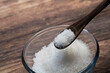 sugar in a wooden tea spoon and sugar in a glass bowl