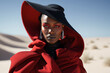 A woman in a red coat and a black hat stands in the desert. Generative Ai