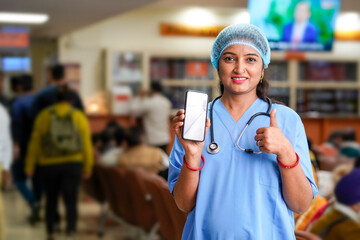 Indian female doctor showing smartphone screen at hospital.