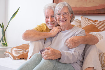 Wall Mural - Love lives forever! Senior couple portrait at home. Handsome old man and attractive old woman are enjoying spending time together while lying in bed.