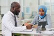 © AnnaStills - African American doctor pointing at tablet pc and discussing difficult disease with his colleague during a meeting in office