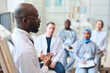 © AnnaStills - African American speaker talking to group of doctors during conference