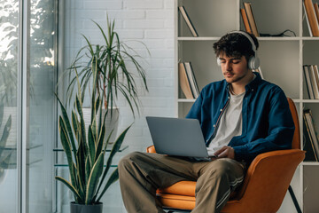 Wall Mural - young male at home with laptop and headphones