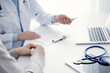 © rogerphoto - Doctor and patient discussing current health questions while sitting at the table in clinic office, only hands closeup. Medicine concept