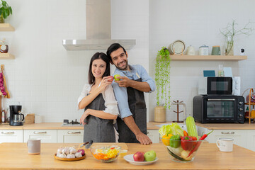 A young couple in love having fun while preparing a breakfast together on a beautiful morning. Couple holding red and green apples to make a healthy salad.