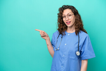 Wall Mural - Young nurse caucasian woman isolated on blue background pointing finger to the side