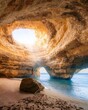 © Withkaejon/Wirestock Creators - Vertical shot of a person standing on the rock, Benagil cave in Algarve, Portugal