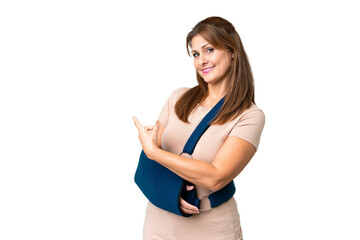 Canvas Print - Middle age with broken arm and wearing a sling over isolated background pointing back