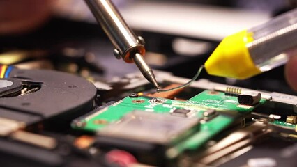 Wall Mural - a man is soldering in a repair shop. repair of the board with a soldering iron