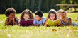 © Nina/peopleimages.com - Children, books and lying in park with friends, learning or diversity for reading at school playground. Kids, education or study with support, mockup space or solidarity at multicultural kindergarten