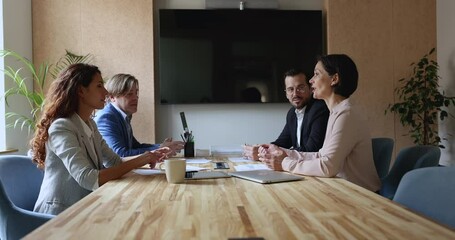 Wall Mural - Confident mature business leader woman talking to colleagues, partners at group meeting table, discussing strategy tasks, brainstorming, giving instructions to team of employees