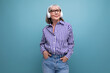 © Ivan Traimak - smiling old generation woman with gray hair listening to music with headphones on a bright studio background