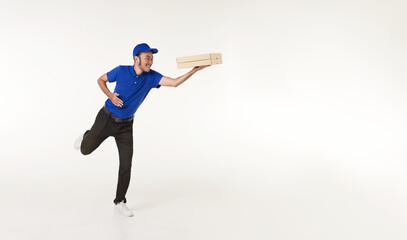 Wall Mural - Asian Pizza delivery man wearing in blue uniform holding fresh food paper box and running isolated over white background. express delivery concept.