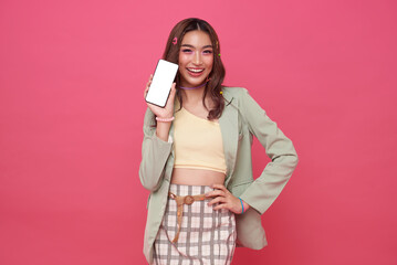 Happy smiling Asian teen woman showing smartphone mockup of blank screen on pink studio background.