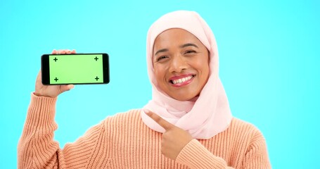 Wall Mural - Islam, phone or green screen and a woman on a blue background in studio holding a display with tracking markers. Muslim, mobile contact and an attractive young female showing a screen for marketing