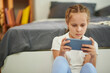 © DragonImages - Preteen girl playing videogame on smartphone