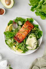 Wall Mural - Baked roasted salmon steak with green healthy salad with avocado. Fresh diet dinner meal. Vitamin food concept on the plate and grey background.