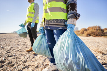 portrait of two activists holding garbage bags. teamwork standing up. volunteers cleaning up plastic