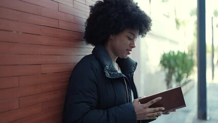 Sticker - African american woman reading book leaning on wall at street