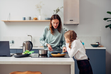 Mother cooks food at home in the kitchen