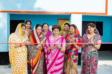 Indian business woman in sari cutting red ribbon while colleagues are clapping hands. Women empowerment.