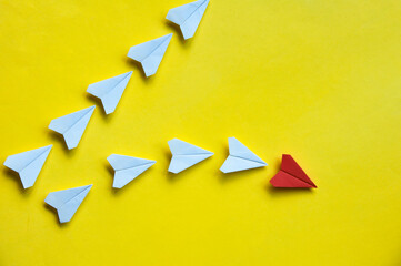 Wall Mural - Red paper airplane origami leaving with other white airplanes on yellow background with customizable space for text or ideas. Leadership skills concept and copy space