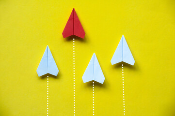 Wall Mural - Top view of red paper airplane origami leaving other white airplane behind on yellow background.