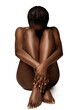 © inarik - Woman Body Skin Care. African Beauty Model embracing Legs sitting over White isolated background. Beautiful naked Girl hidden Face. Women Health and Spa Cosmetology