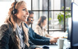 © ty - Portrait of call center worker accompanied by her team. Smiling customer support operator at work.