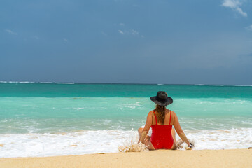 Wall Mural - Woman with reb swimsuit and black hat at the beach in Bali indonesia