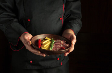 Professional chef serves a serving plate with sliced ham and cheese. Dark free space for recipe or menu