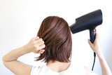 ドライヤーで髪を乾かす女性