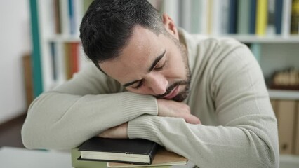 Sticker - Young hispanic man student sleeping with head on books at library university