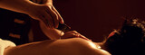 Masseur pouring aroma oil on back woman customer in cosmetology spa centre.