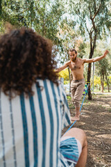 Wall Mural - Two men slacklining in city park during summer day