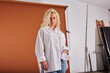 © Flamingo Images - Blonde woman standing in a white shirt against an orange backdrop