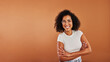 © Flamingo Images - Young woman smiling with her arms crossed on an orange background