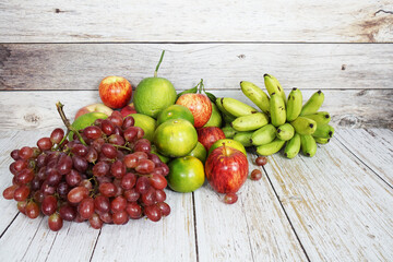 Poster - Various of fruits with Red grape, red apple, banana and green orange on wooden background