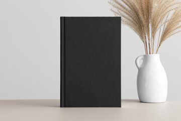 Canvas Print - Black book mockup with a reed pampas decoration on the beige table.