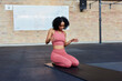 © Flamingo Images - Smiling woman kneeling on a mat in a gym