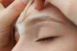 Correction Eyebrow hair waxing. Master combs eyebrows of woman in beauty salon