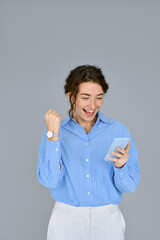 Wall Mural - Young happy professional business woman feeling excited winner looking at cellphone using mobile phone receiving great news, new job offer, celebrating online win results standing at gray background.