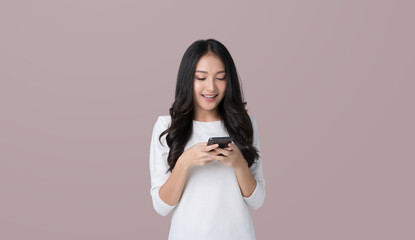 Wall Mural - Young Asian woman texting message using mobile phone application on isolated brown background